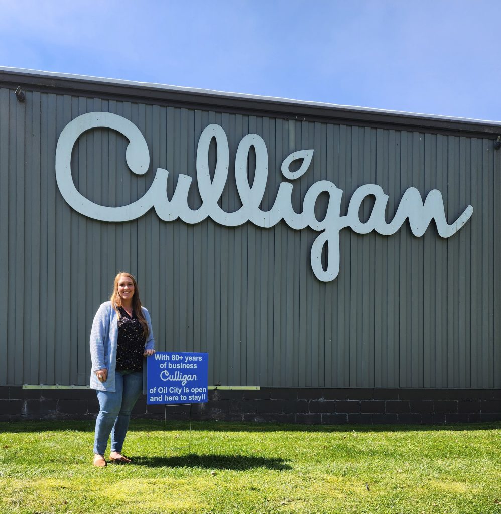 Kayla, culligan manager stands in front of business while celebrating 1 year as manager